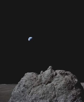 A photo of Earth from the Moon's surface, showing a rocky foreground and the Earth in the dark sky above.